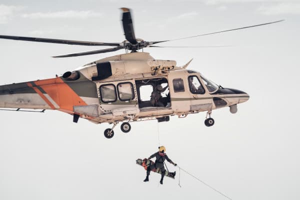 A rescue helicopter lifts a responder and patient